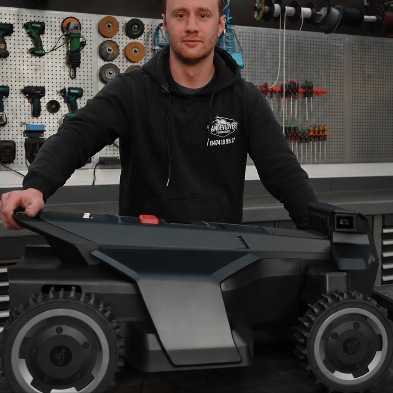 Person in a workshop with a lawn mower and tools on the wall.