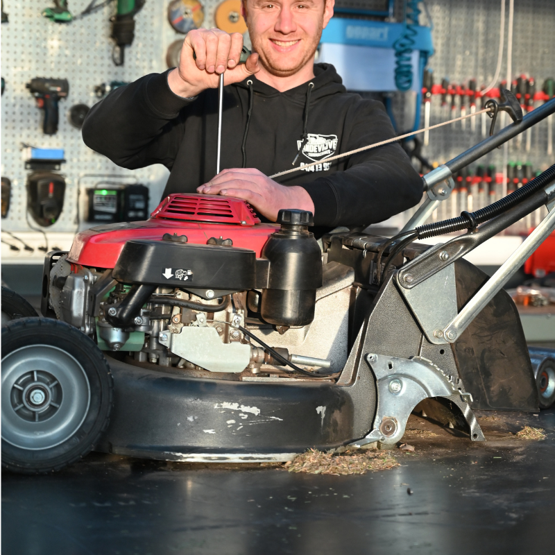Person working on a lawn mower with text about repair services in Dutch.