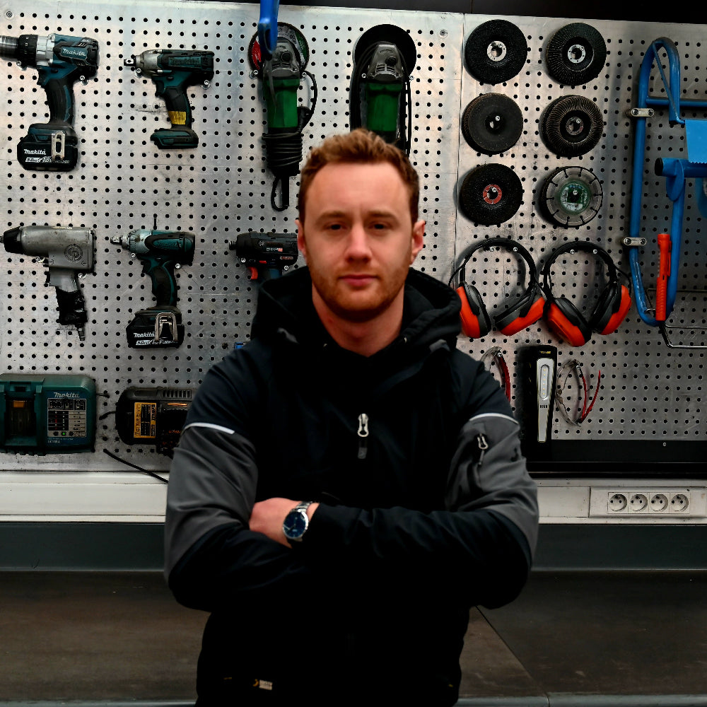 Man standing in front of a pegboard with tools and equipment