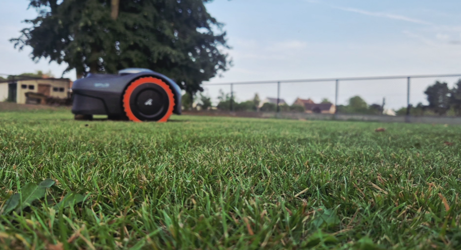 A lawn-mowing robot drives over a perfectly trimmed lawn.